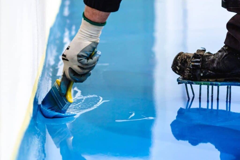 Perth Epoxy group worker levelling blue Epoxy for Car Park Flooring in Maddington